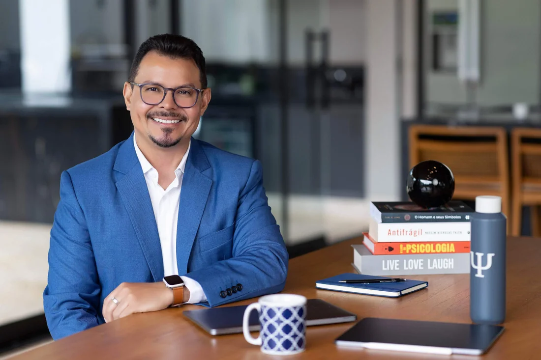 Mariano de Deus em sua mesa de trabalho, com livros de psicologia